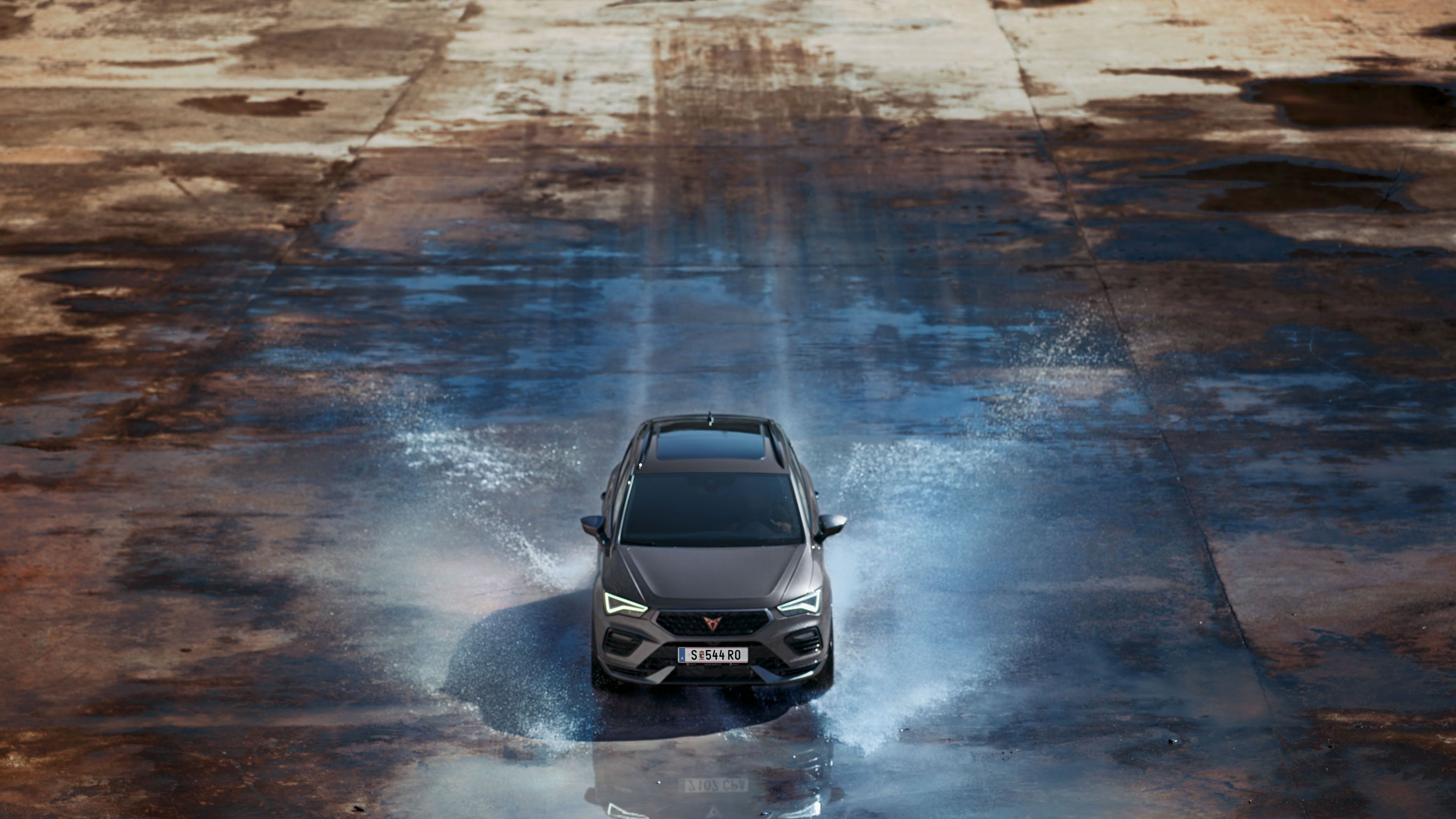 Frontansicht des CUPRA Ateca bei der Fahrt durch das Wasser, mit betonter Motorhaube, Voll-LED-Scheinwerfern, dunklen Aluminiumdetails und Hochleistungsbremsen mit Brembo-Bremssätteln.