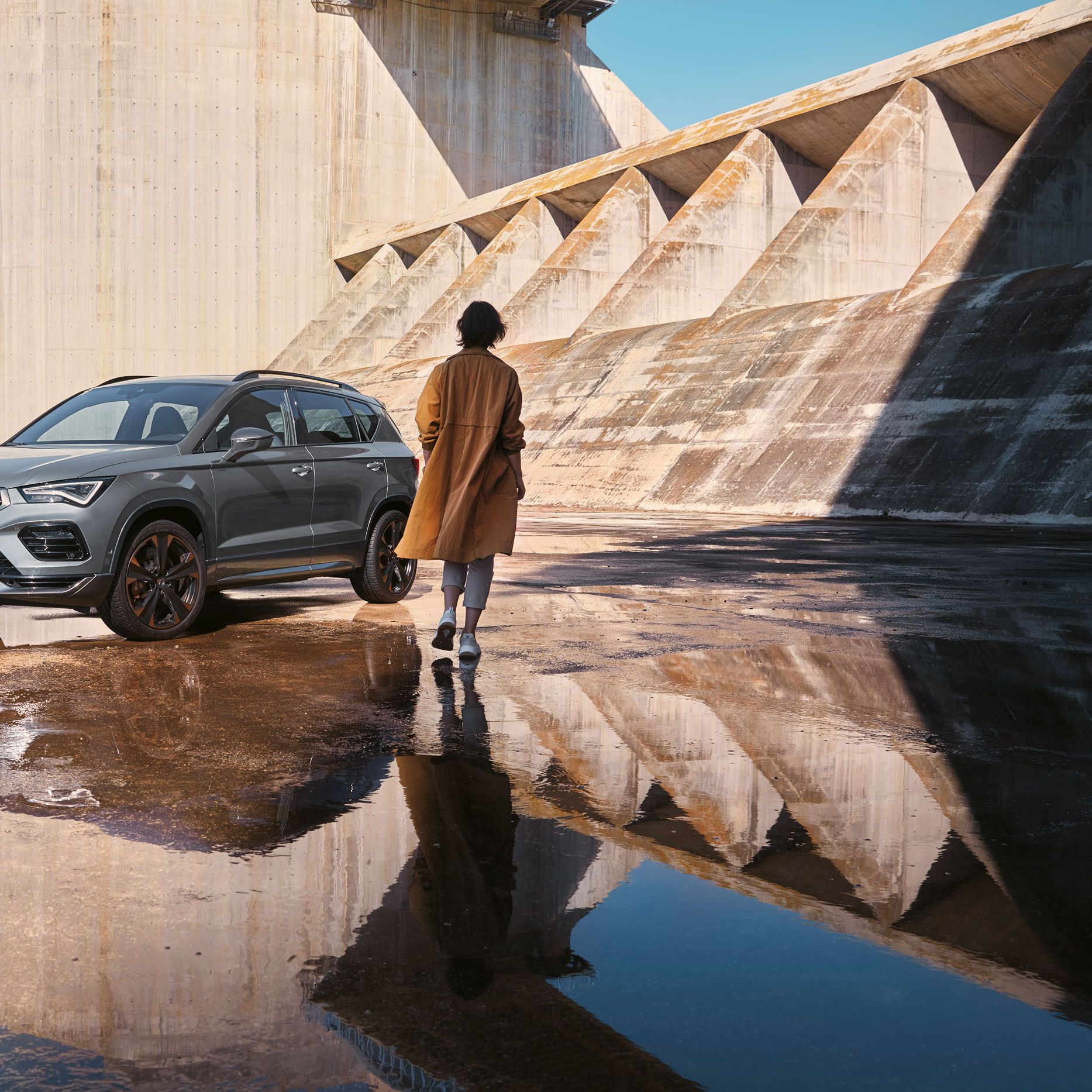 Eine Person geht auf einen CUPRA Ateca zu, der die markanten, athletischen Linien und die dynamische Form zeigt, die den Geist der CUPRA Tribe verkörpern.