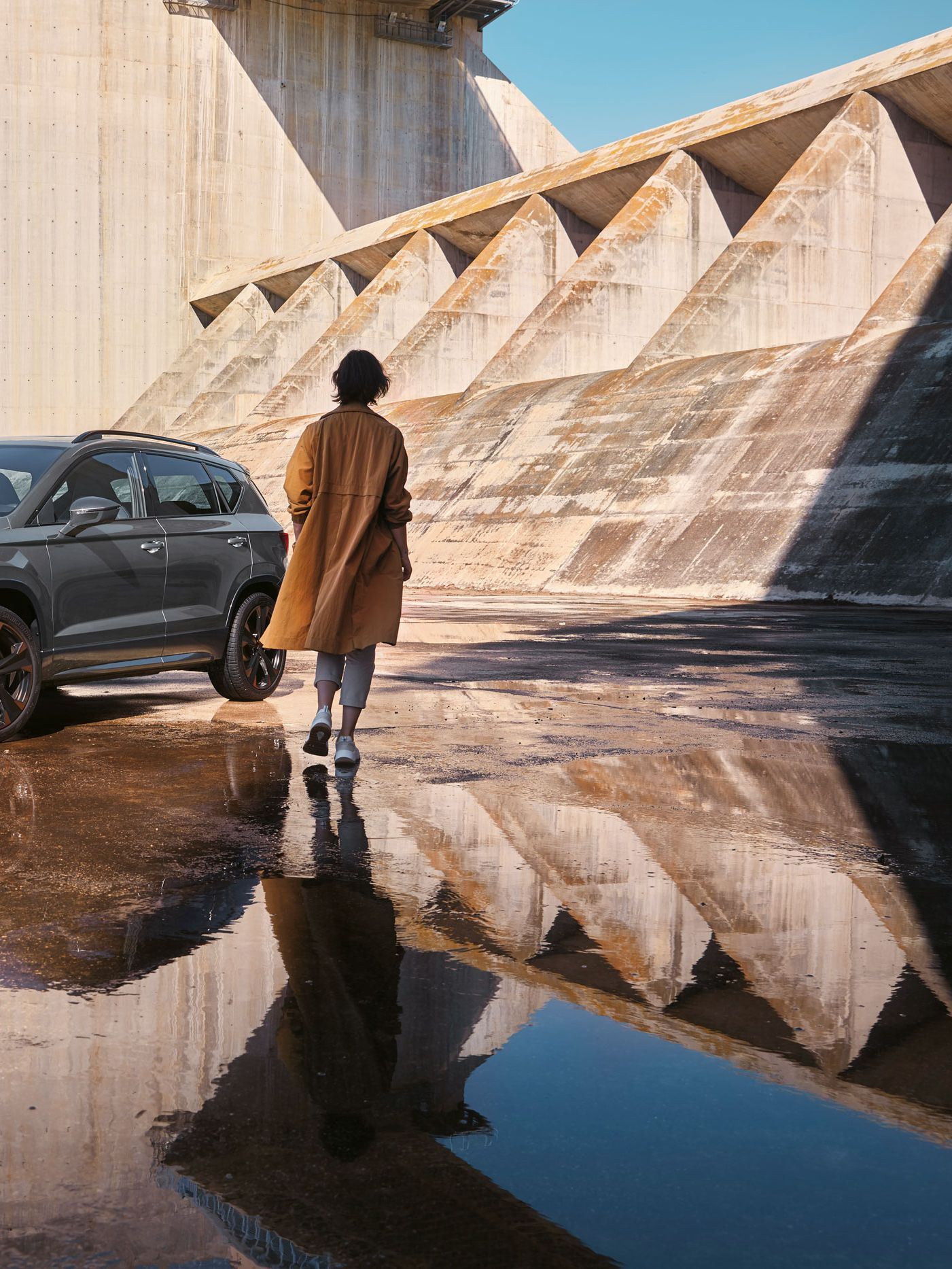 Eine Person geht auf einen CUPRA Ateca zu, der die markanten, athletischen Linien und die dynamische Form zeigt, die den Geist der CUPRA Tribe verkörpern.