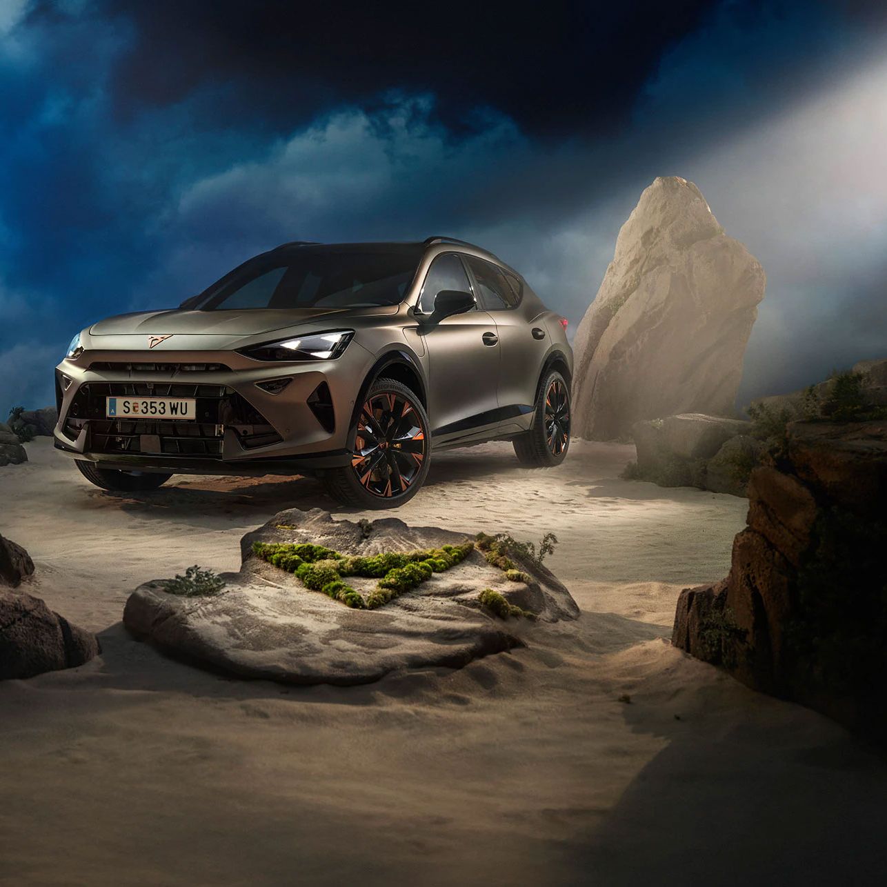 Ein CUPRA Formentor VZ in Bronze steht dramatisch beleuchtet in einer felsigen, nebeligen Landschaft. Eine Lichtstrahl beleuchtet das Fahrzeug und betont seine Konturen. Im Hintergrund sind Felsen und Pflanzen zu sehen.