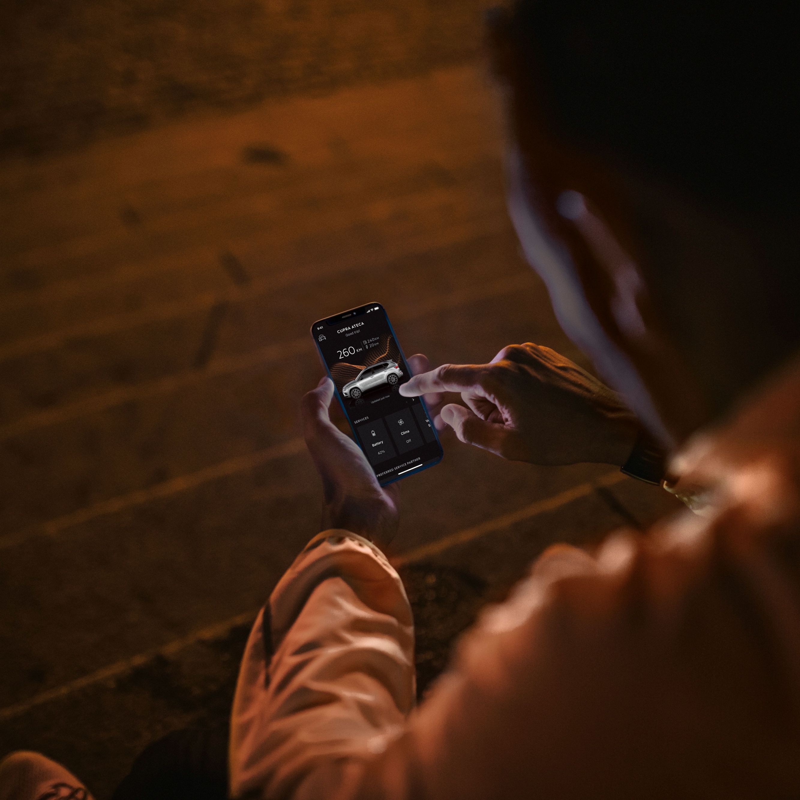 Die CUPRA CONNECT Online-Dienste umfassen eine Vielzahl von Lösungen, die auf die Herausforderungen des modernen Lebens reagieren. Eine Person sitzt nachts auf Treppenstufen und nutzt ein Smartphone, das vom Bildschirm beleuchtet wird.