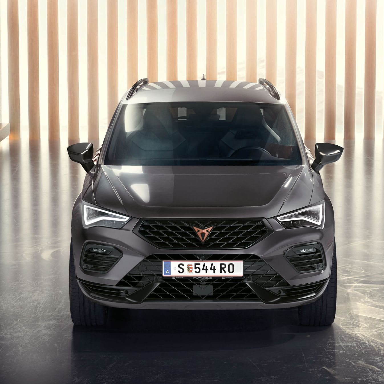 Frontansicht des CUPRA Ateca, ein grauer SUV in einer modernen, beleuchteten Umgebung. Das Bild hebt den markanten Frontgrill, die LED-Scheinwerfer und das schlanke Design hervor.