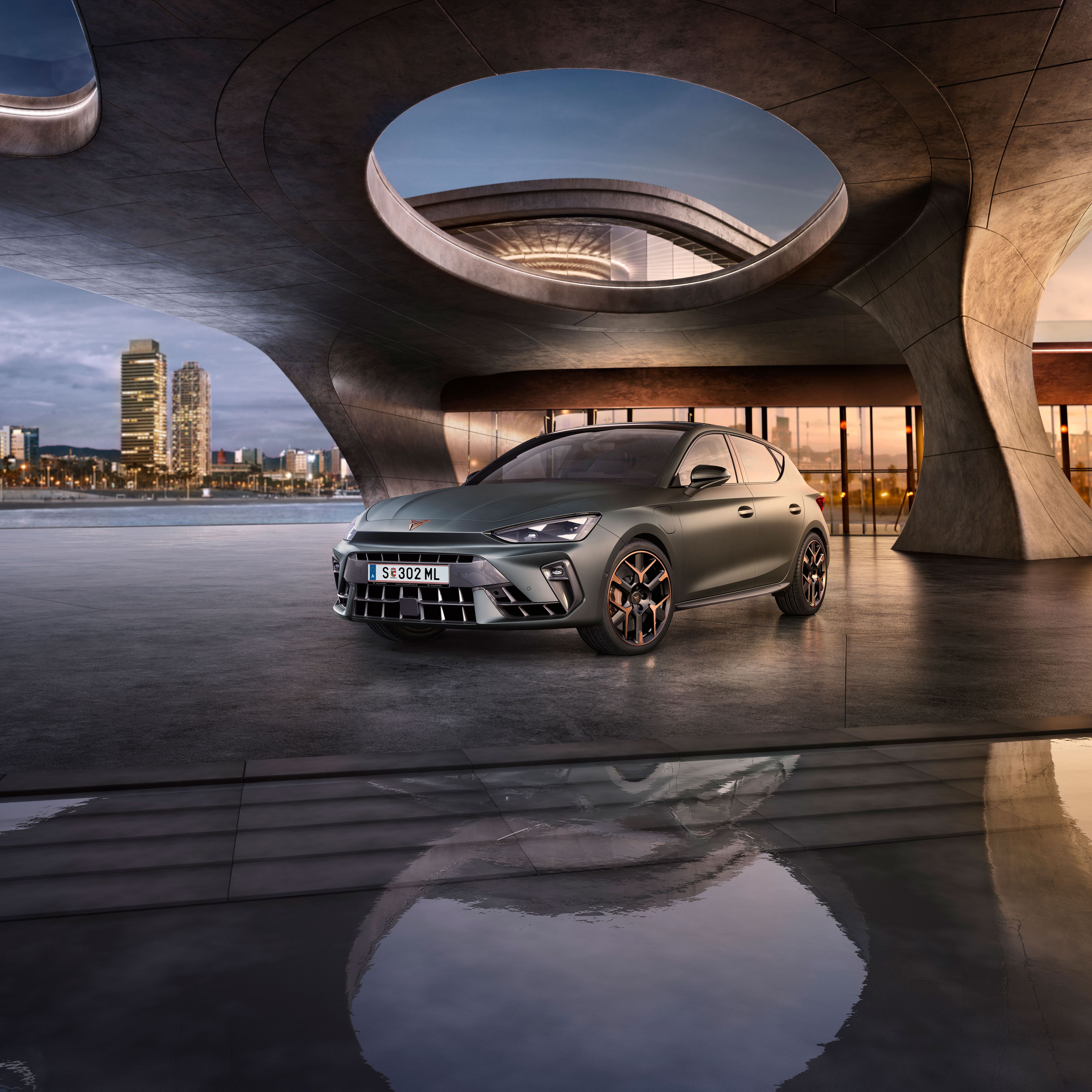 Schräge Vorderansicht eines grauen CUPRA Leon, der in einem modernen Parkhaus parkt.